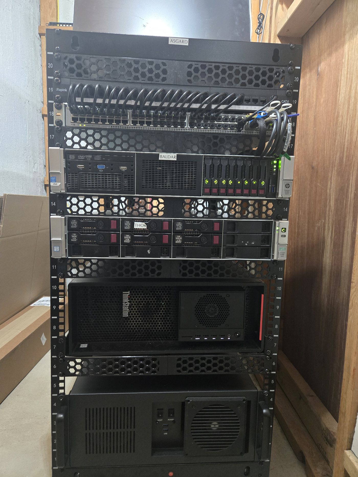 Enterprise rack in a home workshop: Cisco Nexus switch, two HP ProLiant DL380 Gen9 servers, patch panel with cable management